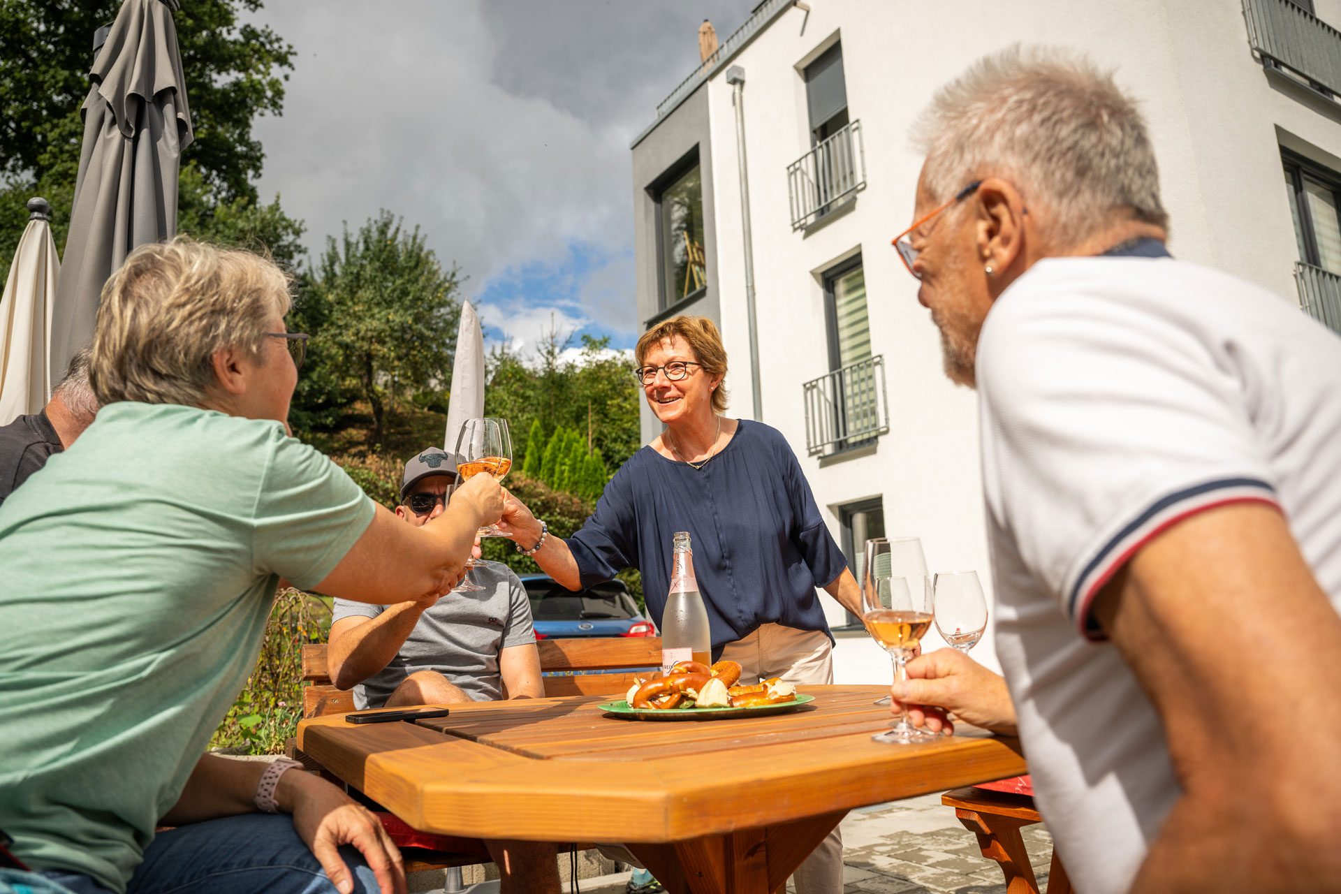 Eine Gruppe Rentner stößt im Hinterhof eines Hauses mit Sekt an.