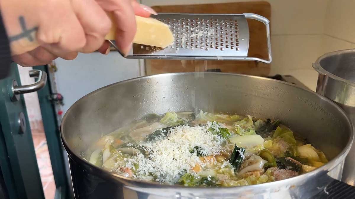 Mammaculinaria reibt Parmesan auf die fertige Minestra di Napoli, ihr Rezept für das Heilig’s Blechle Magazin