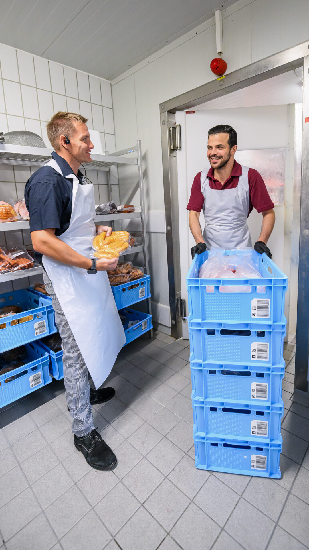 Ronald Petermann und George holen Fleisch und Würste aus dem Kühlraum der Edeka-Fleischabteilung.