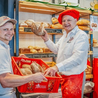Julian und Hermann Schöllkopf legen frisch gebackene Sauerteig-Brote in die Auslage im Laden.