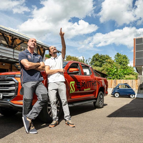 Michael und Oliver lehnen am Firmenwagen im Hof und blicken nach oben, von wo die Energie für Ihre E-Fahrzeuge kommt.