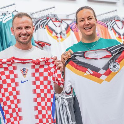 Melanie und Zoran halten das deutsche und das kroatische Weltmeisterschaft-Trikot 2026 in die Kamera.