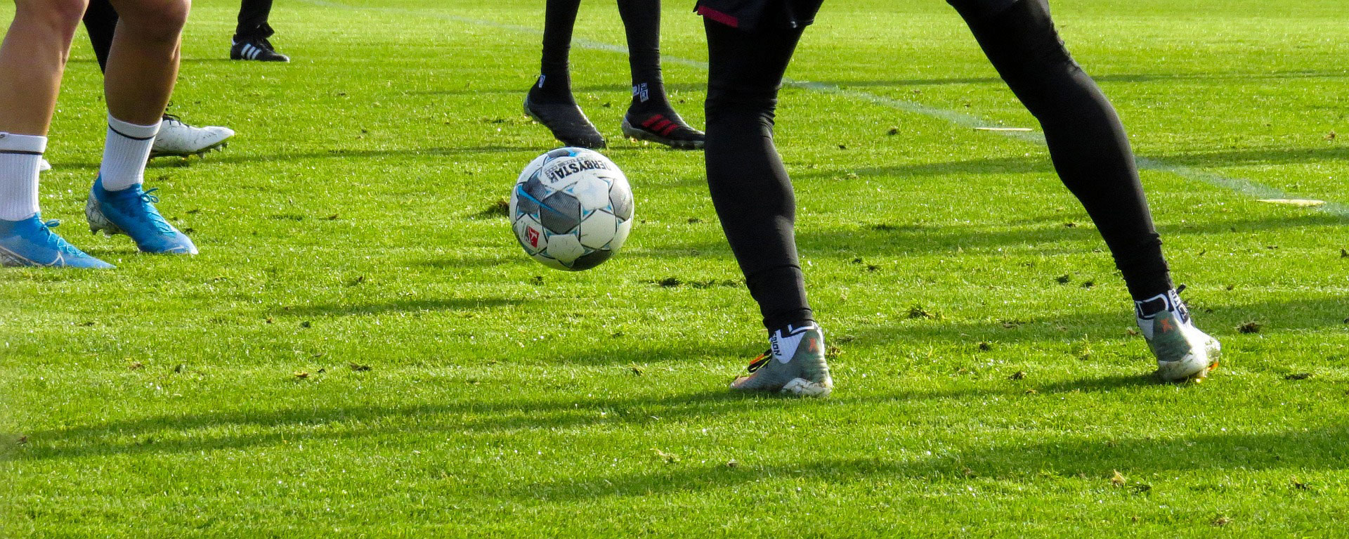 Beine von Fußballern auf dem Platz